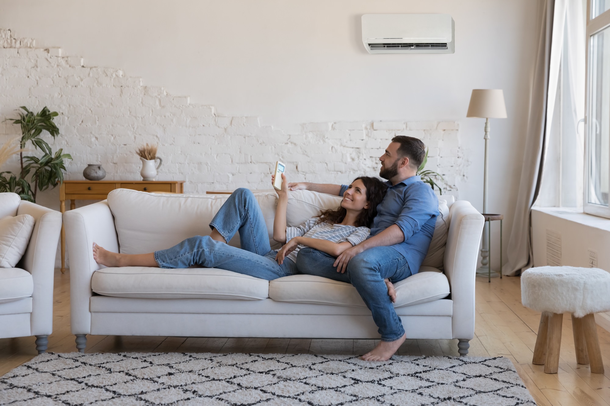 Happy Millennial Couple Of Homeowners Enjoying Cool Conditioned Air Resting