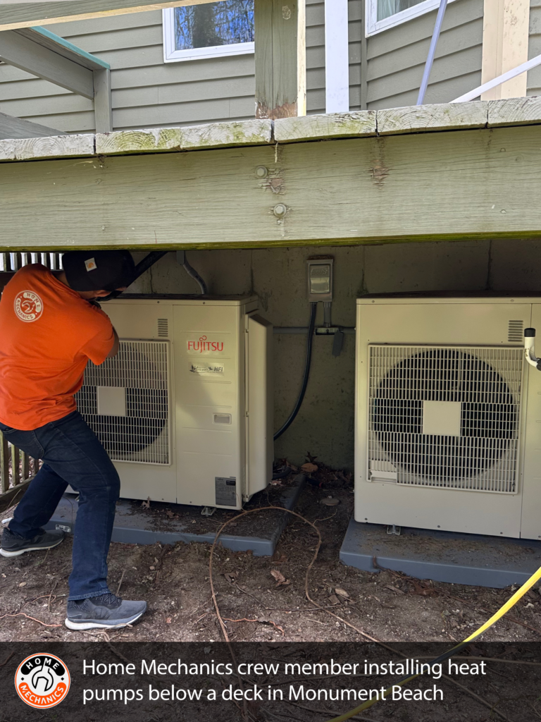 Two heat pumps installed by Home Mechanics under a deck at a home in Cape Cod